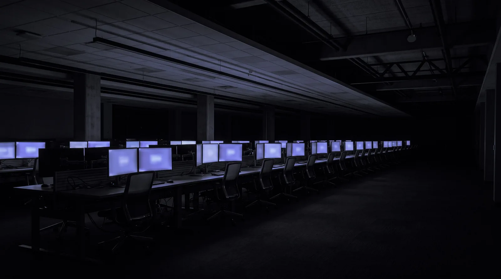An empty overnight operations floor, every monitor lit, no one at the desks.